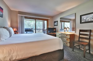 Main bedroom includes a flatscreen TV, large mirror and wooden dresser
