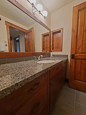 En suite fifth bathroom with gorgeous upgraded vanity with single sink with multicolored granite countertops and beautiful cabinetry