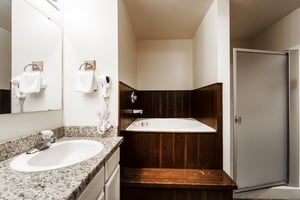 The shared guest bathroom includes white cabinets, granite countertops, a deep soaking tub and walkin shower