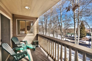 The private patio looks over a grove of Aspen trees and has green Adirondack chairs