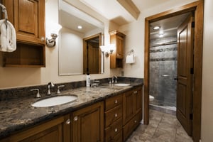 Ensuite main bathroom with granite countertop double vanity and wooden cabinetry