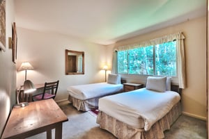 Guest bedroom with two twin beds or king bed with advance notice, work or study desk and large picture window overlooking the aspens