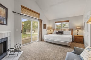 The spacious main suite with a king size bed, large windows, and gas burning fireplace.