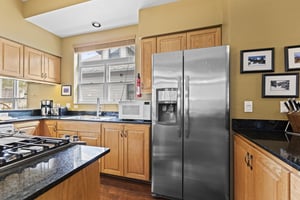 The kitchen has a stainless steel refrigerator and wood cabinets.