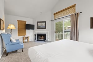 The spacious main suite with a king size bed, large windows, and gas burning fireplace.