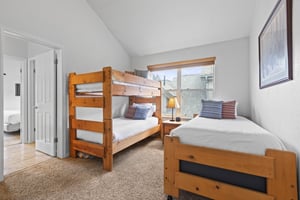 A bedroom has twin bunk beds and an additional twin bed.