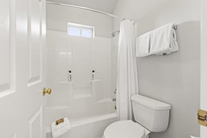 The bathroom in all white with a bathtub and shower combination.
