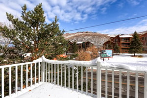 Upper level balcony with scenic view of snowy pines and blue skies