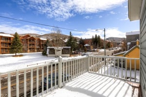 Upper level balcony with scenic view of snowy pines and blue skies