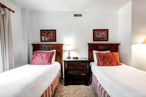 The second bedroom offer two twin beds with wooden furniture.
