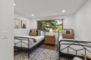 The second bedroom has a double bed and a twin bed and black bed frames.