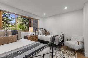 The second bedroom has a double bed and a twin bed and black bed frames.
