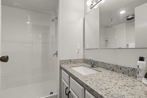 The shared bathroom offers a walkin shower and single sink vanity.