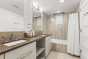 The en suite bathroom has a two sink vanity and a bathtub and shower combination.