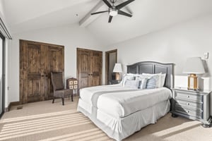 The main suite has a queensize bed, tan carpet, and wooden closet doors.