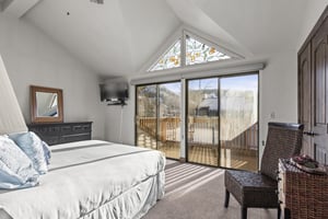 The main suite has a queensize bed, flatscreen TV, and large sliding glass doors with mountain views.