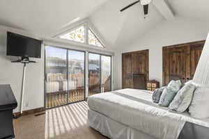 The main suite has a queensize bed, flatscreen TV, and large sliding glass doors with mountain views.