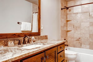 The guest bathroom has a one sink vanity with a bathtub and shower combination.