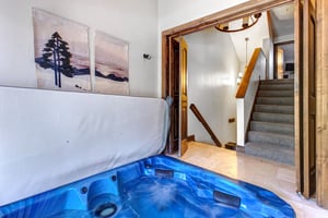 Queen Esther 2425s indoor hot tub with modern landscape art on the wall and entry to the stairwell.