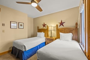 The second bedroom has two twin beds and wooden furniture.