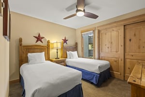 The second bedroom has two twin beds and wooden furniture.