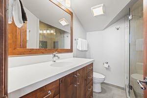 The en suite bathroom offers a single sink vanity and fresh white walls.