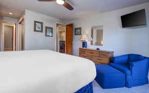 The main suite has a king size bed and wooden furniture.
