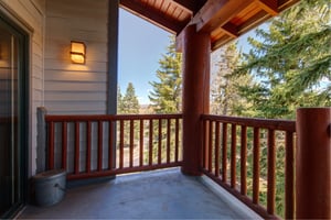 Snow Flower 31s deck with wooden railing and evergreen trees and blue sky beyond.