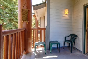 Snow Flower 31s deck with wooden railing and green chairs and side tables.