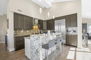 Open concept kitchen with waterfall island and stainless steel appliances.