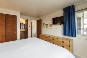 The kingsized bed in the main bedroom with wood furnishings.