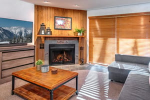 The living room has comfortable couches, gas burning fireplace and wood blinds. .
