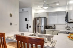 The kitchen offers a breakfast bar with seating for two guests and stainless steel appliances.