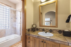 The en suite bathroom with a single sink vanity and bathtub and shower combo.
