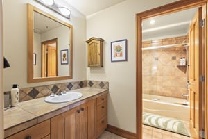 The en suite bathroom has a single sink vanity and bathtub and shower combination.