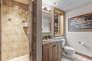 The shared bathroom has a walkin shower and single sink vanity.