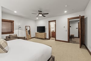 The spacious main suite has a floor mirror, dresser, and flat screen TV.