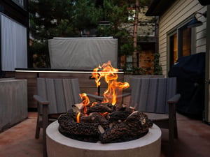 The fire is burning in the gas firepit with two cozy chairs behind it.