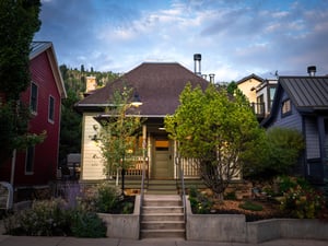 The front of Town Lift Chalet has inviting stairs leading to a cream color home with green trim and door.