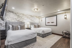 Two queen beds in the lower level bedroom with hardwood floors and large area rug
