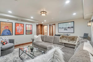 Lower level game room with comfortable sectional and modern glass topped coffee table