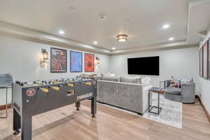 Lower level game room with hardwood floors, large area rug, foosball table and large TV