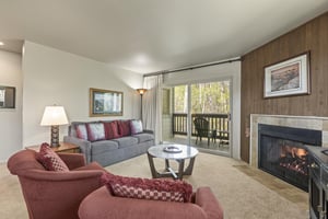 The living room offers comfortable furniture and a cozy fireplace and double doors leading to a private patio..