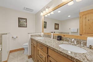 The en suite bathroom has a double sink vanity.