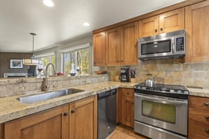 The kitchen has warm wood cabinetry, stainless steel appliances, and granite counter tops.
