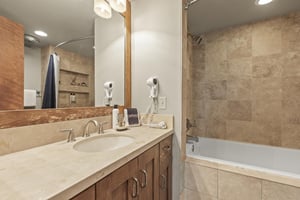 The en suite bathroom has a single sink vanity and bathtub and shower combination.