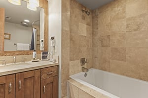 The en suite bathroom has a single sink vanity and bathtub and shower combination.