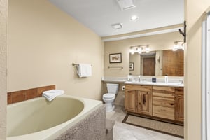 The en suite bathroom has a deep soaker bathtub and double sink vanity.