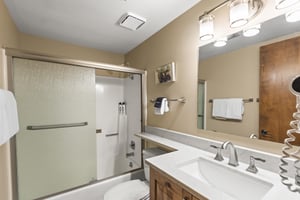 The shared bathroom has a combination shower and bathtub and single sink vanity.
