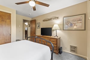 The third bedroom has a queen size bed and wood dresser.